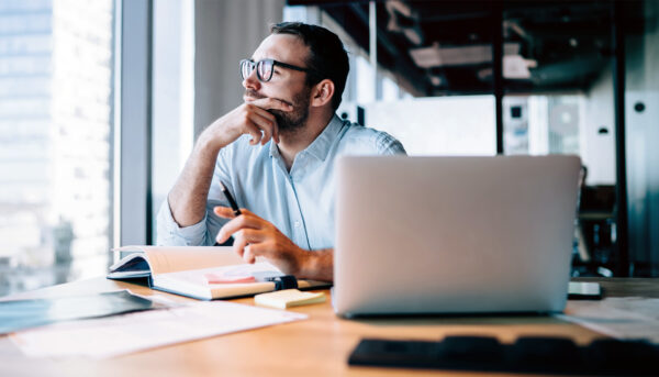 man looking contemplatively out window while working in office