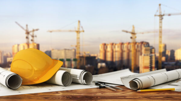 hardhat and blueprints with construction site in the background