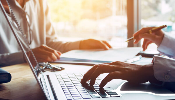 two people in a meeting with laptop and documents